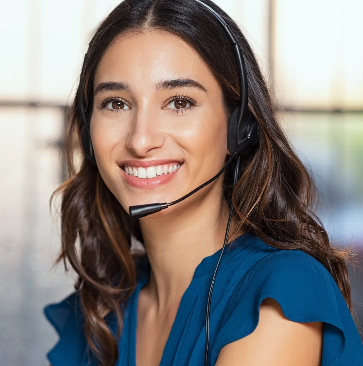 A woman wearing a headset is smiling and wearing a blue shirt