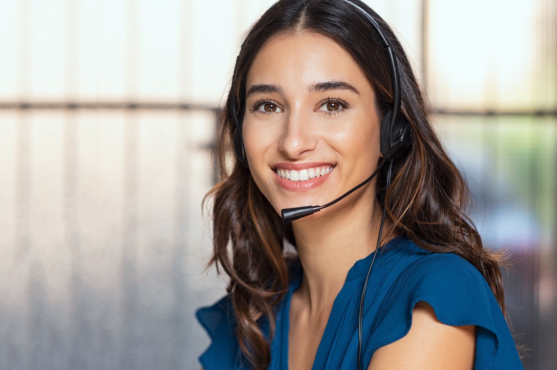 A woman wearing a headset is smiling and looking at the camera.