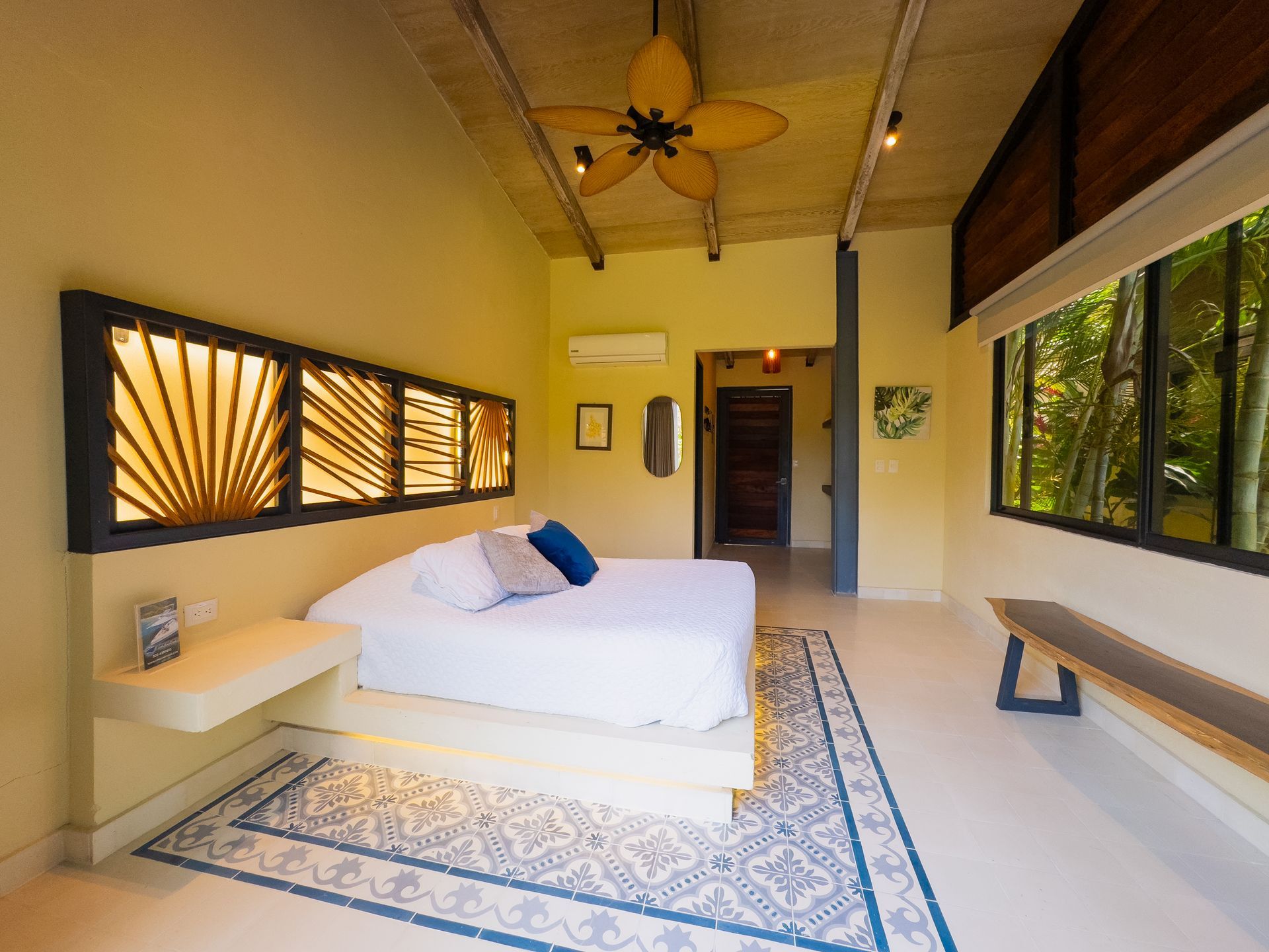 Bedroom with a king bed, decorative headboard, and large window overlooking trees.