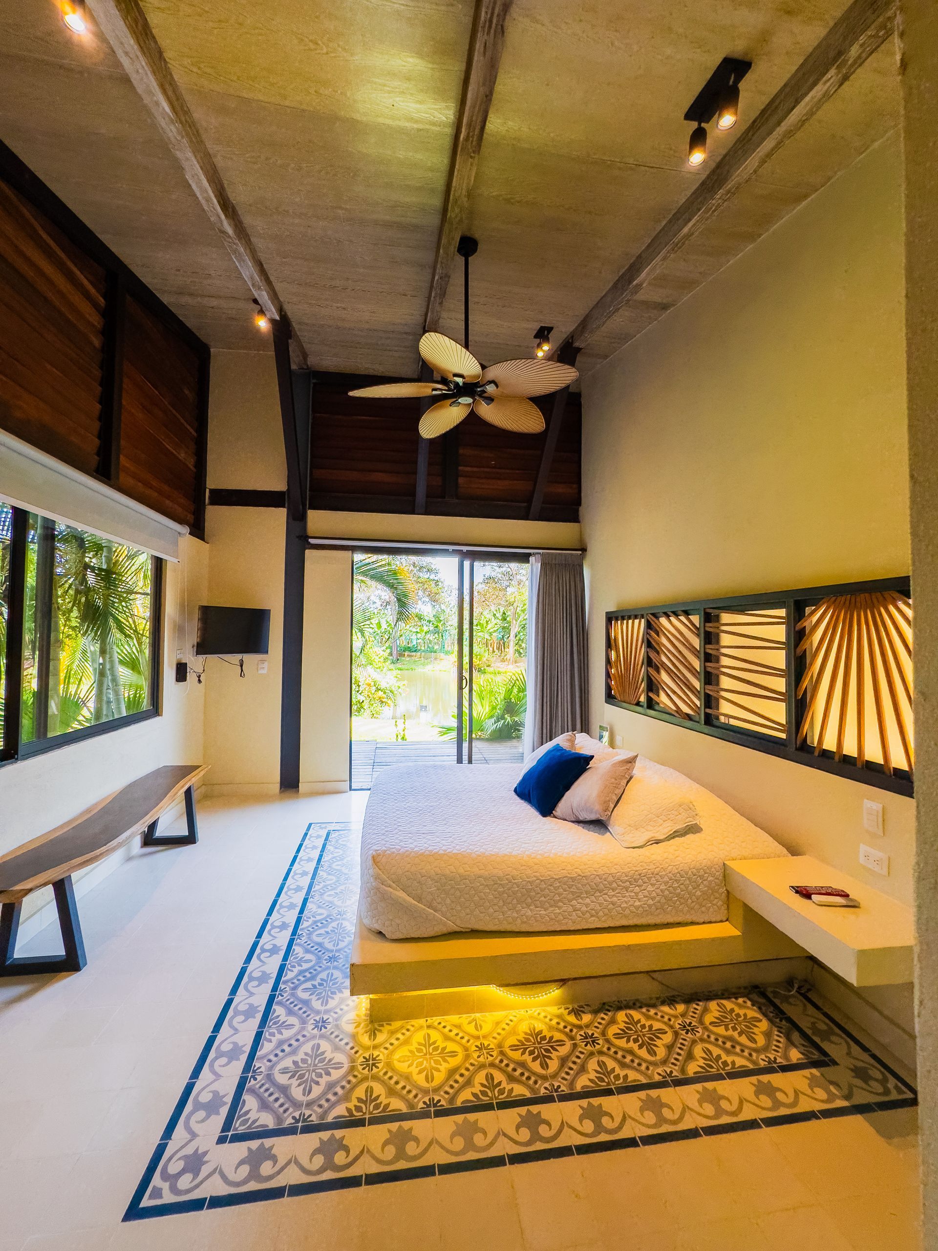 Modern bedroom with bed, outdoor view, and unique tile flooring. Beige and wood tones.