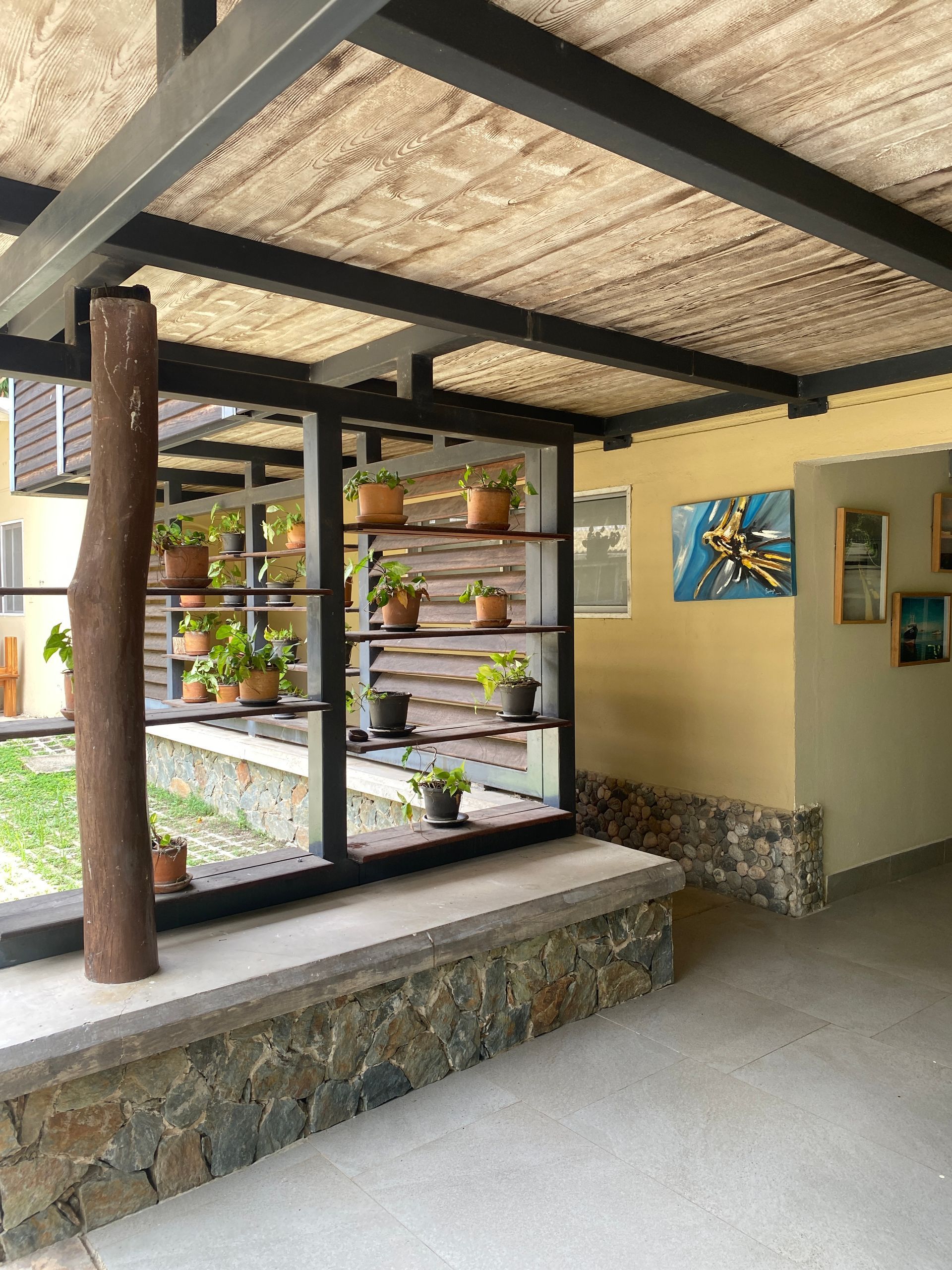 Outdoor space with plants on shelves, under a covered structure with stone and wood accents.