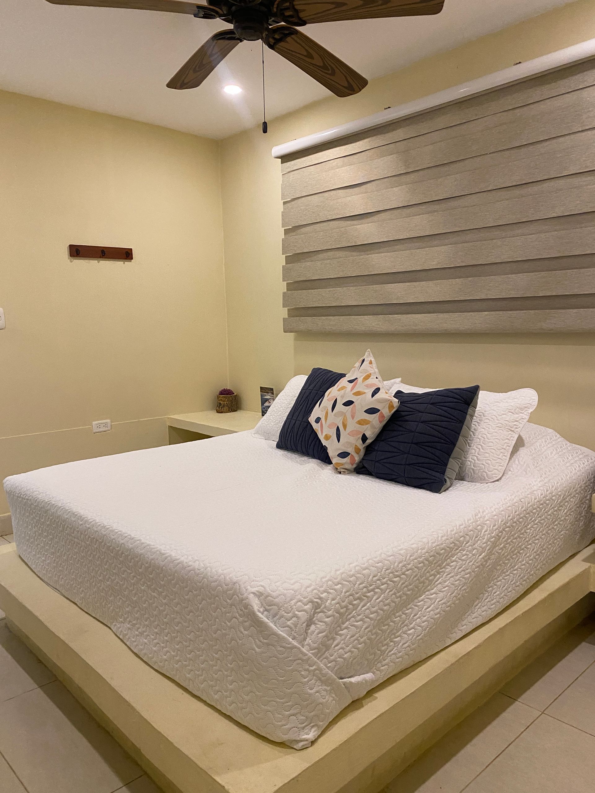 Bedroom with a bed, pillows, and a window with a shade; neutral colors.