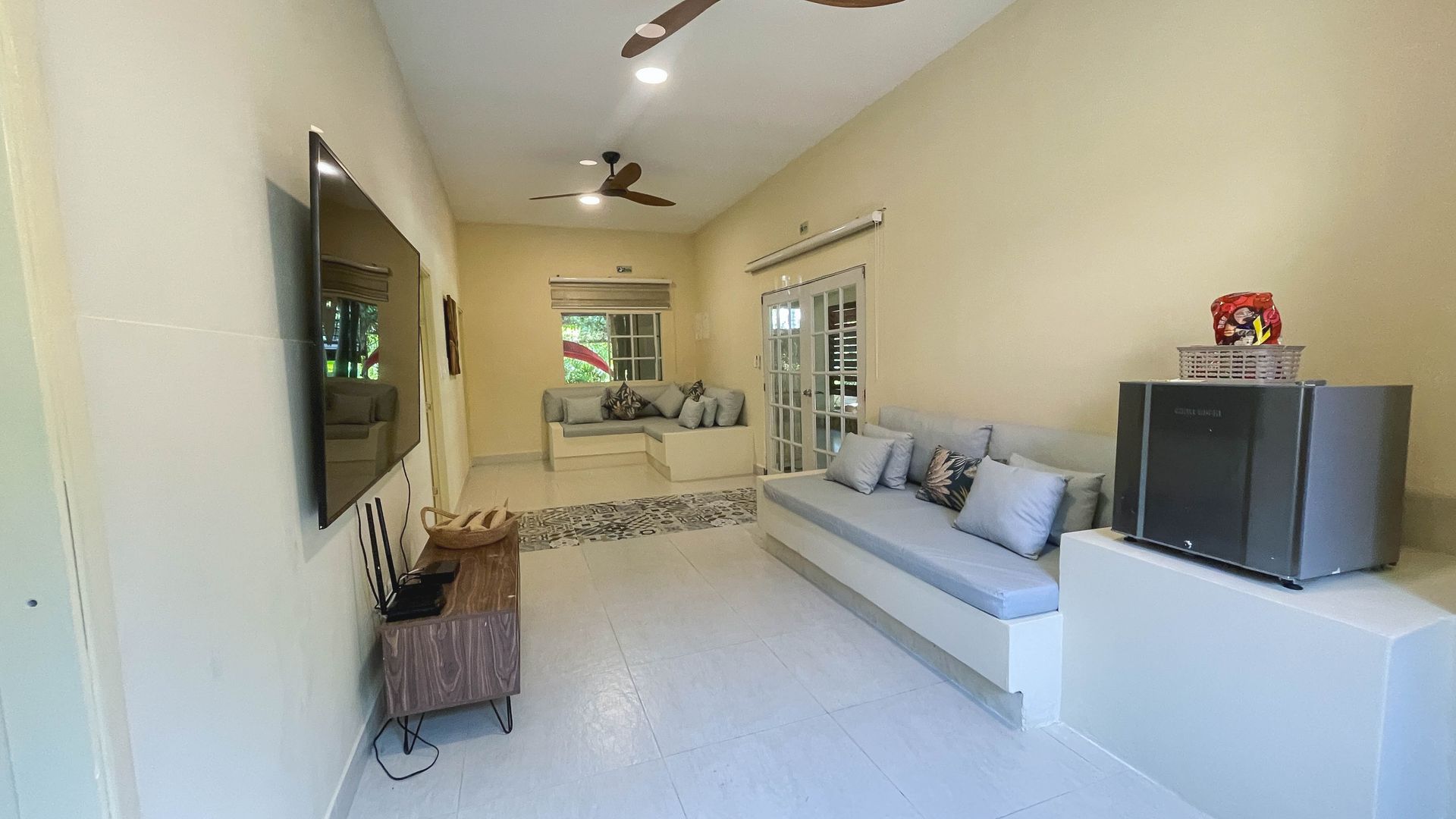 Living room with light walls, built-in sofas, TV, and a stereo.
