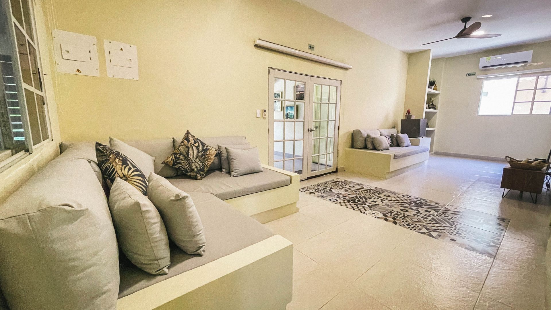 Living room with built-in seating, light yellow walls, and a patterned rug.