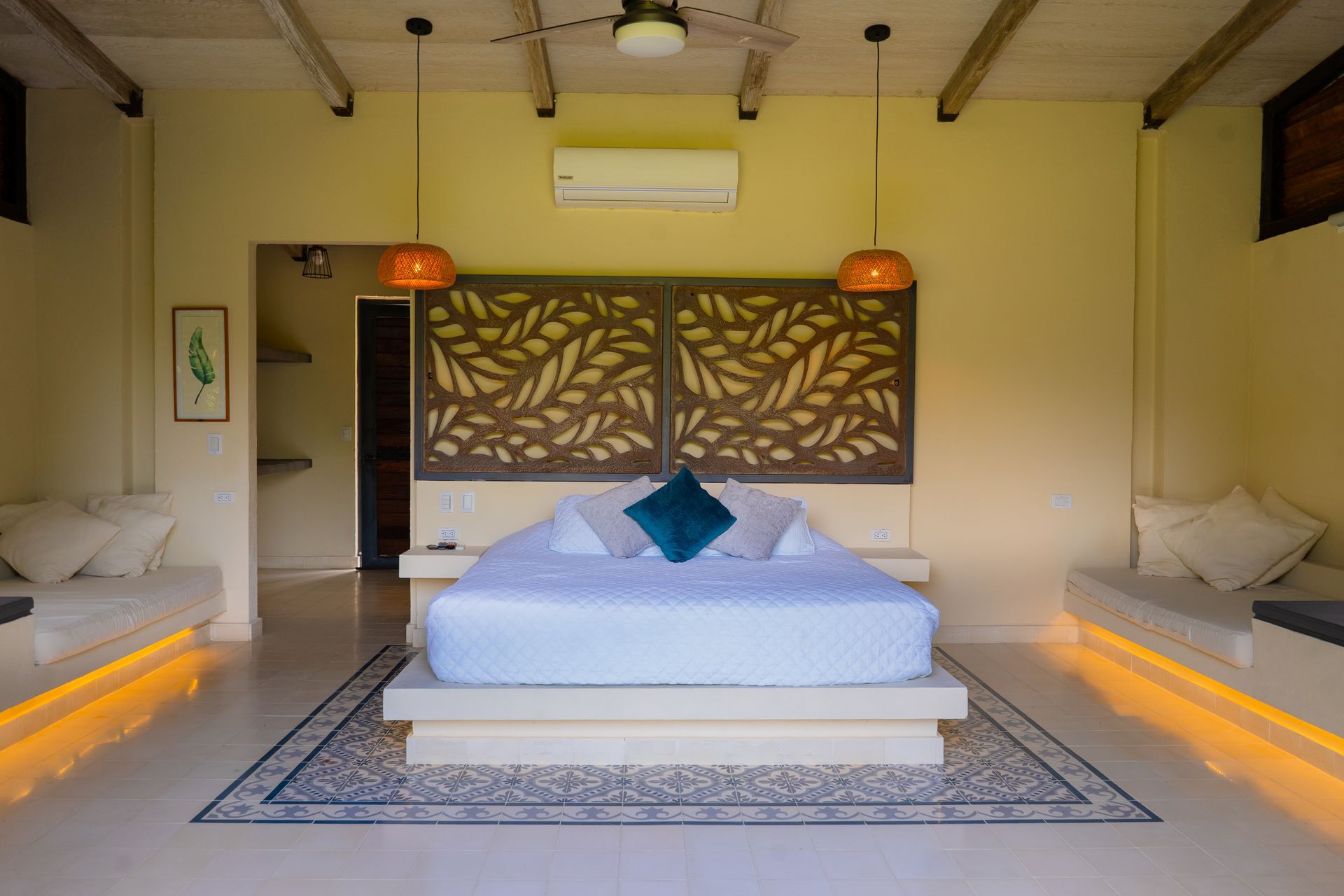 Bedroom with a large bed, decorative wooden headboard, and built-in benches with soft lighting.