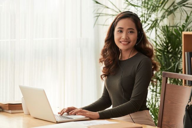 A woman is sitting at a desk using a laptop computer.