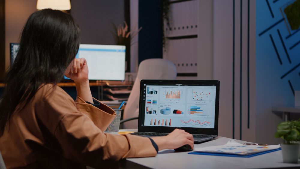 A woman is sitting at a desk using a laptop computer.