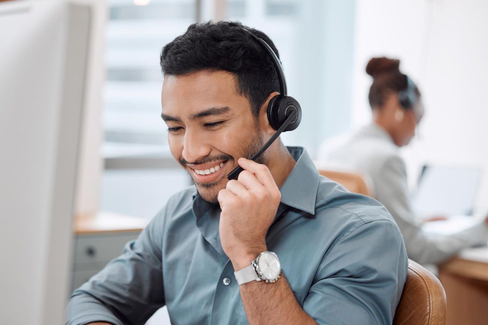 A man wearing a headset is sitting in front of a computer.