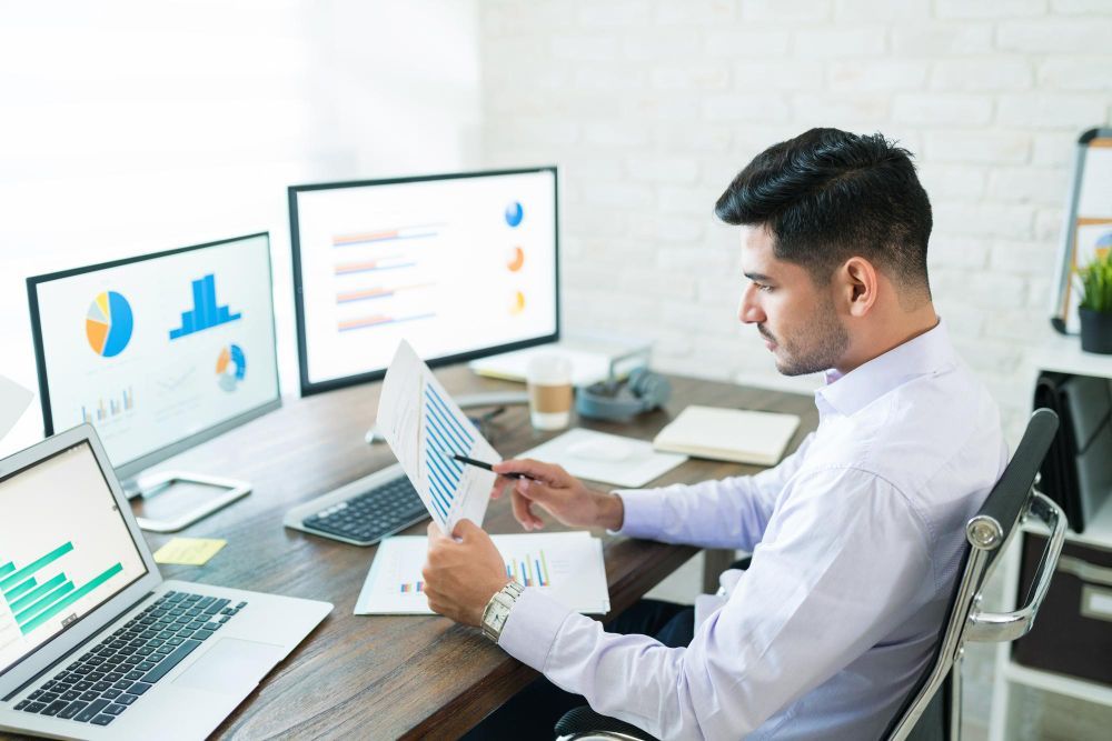 A man is sitting at a desk looking at a piece of paper.