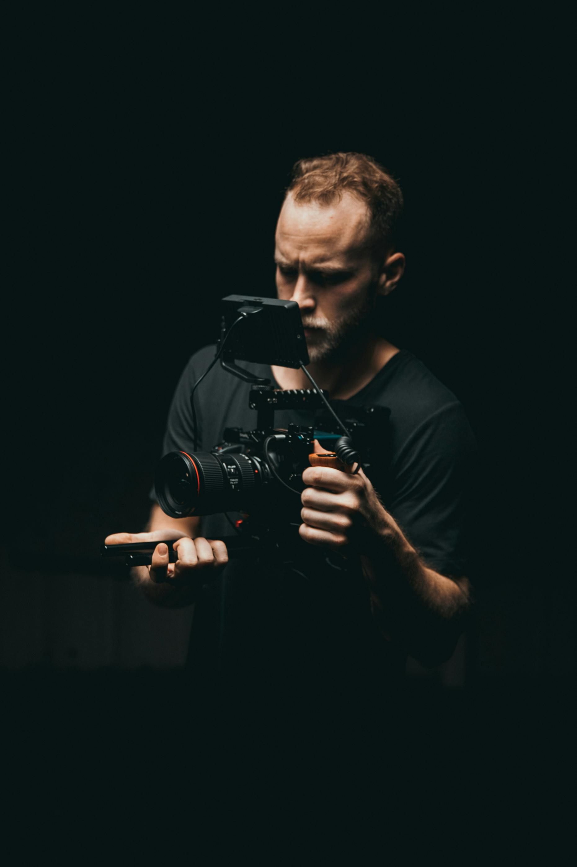 A man is holding a camera in his hand in a dark room.