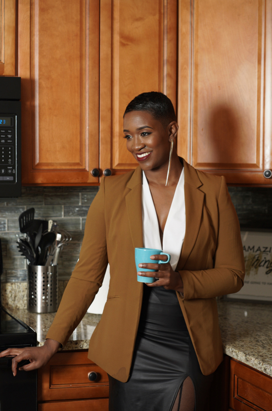 A woman is sitting at a desk with a laptop and a vase of flowers.