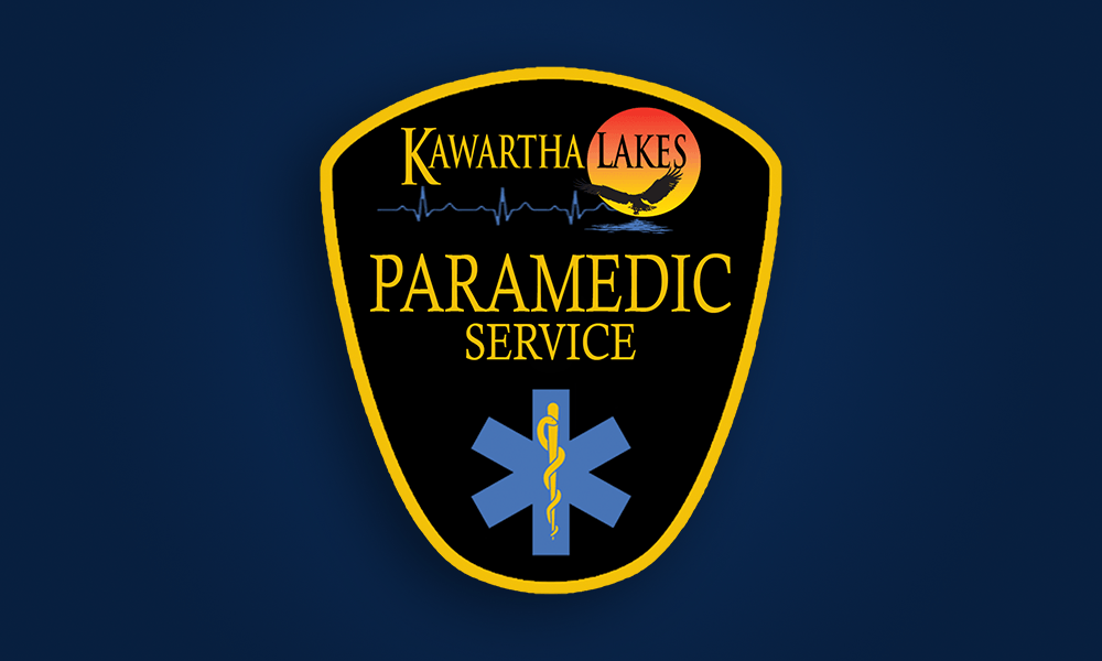 Kawartha Lakes Paramedic Service logo: shield with text, medical star, and sunset over water.