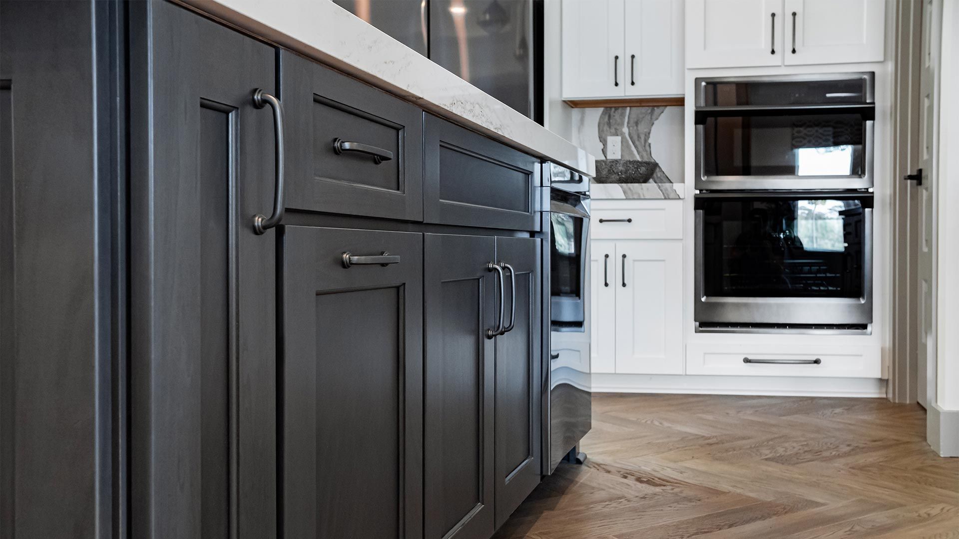 A kitchen with black cabinets and white cabinets and stainless steel appliances.