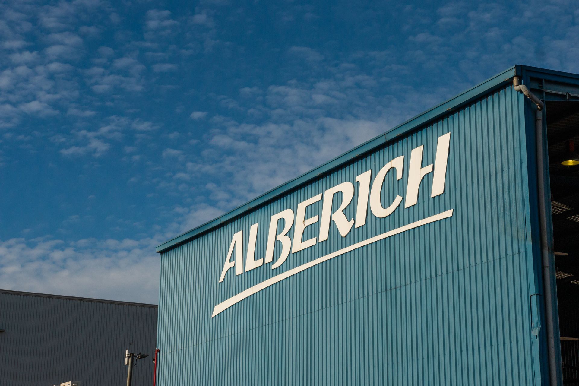 Blue Alberich building sign with white lettering against a blue sky.