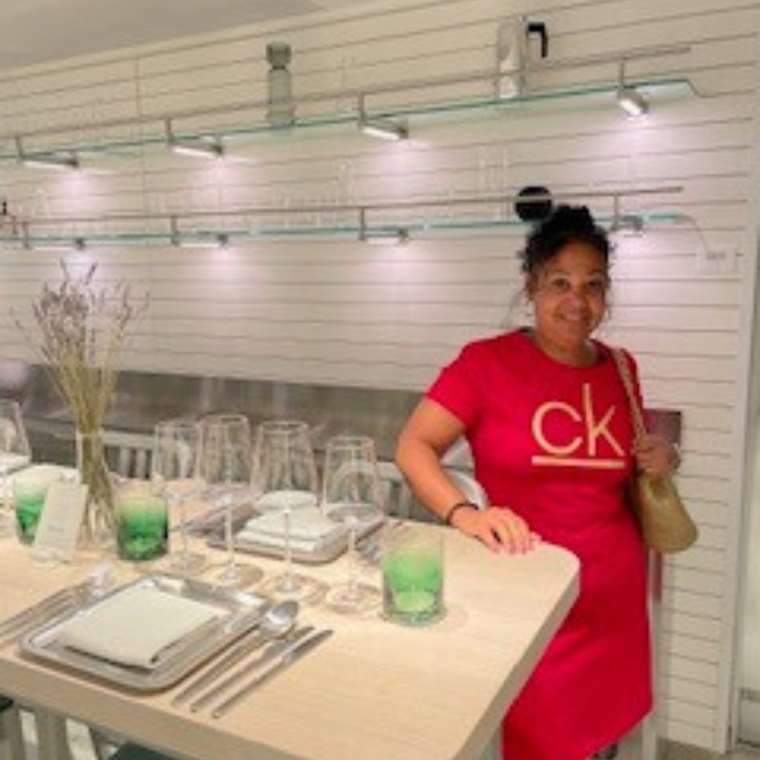 A woman in a red ck shirt stands in front of a table