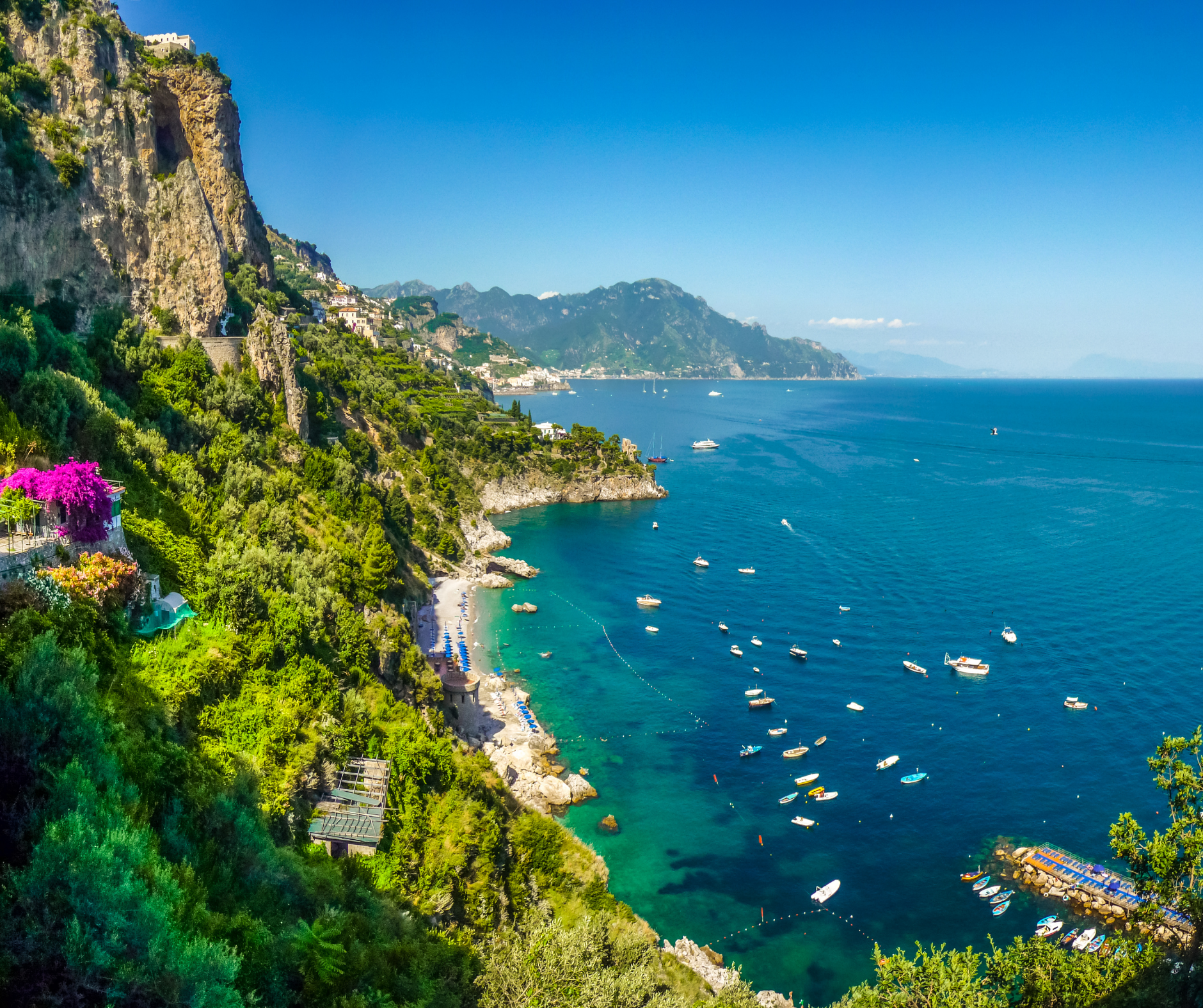 A view of a cliff overlooking a body of water with boats in it.
