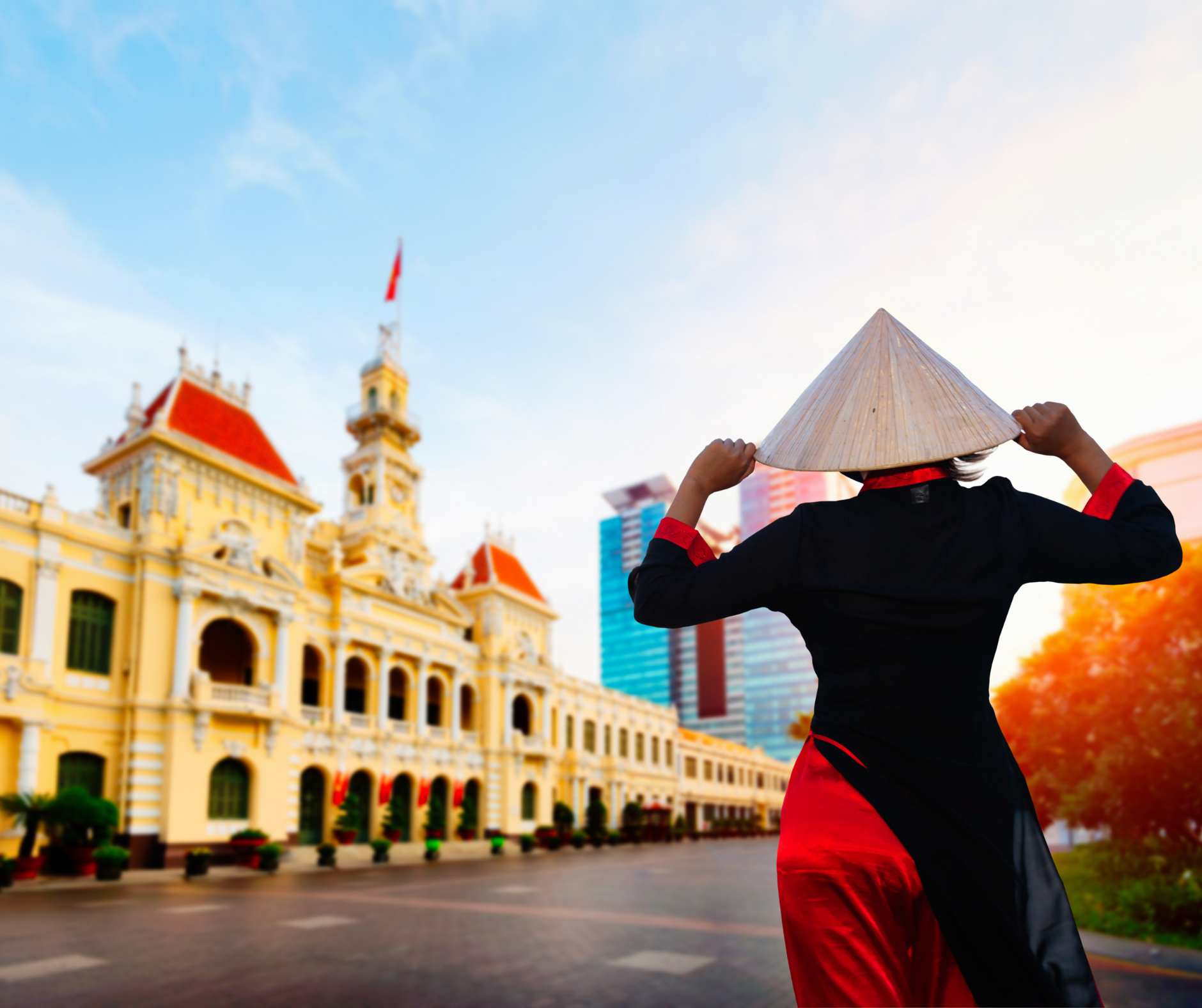 A woman wearing a conical hat is standing in front of a building.