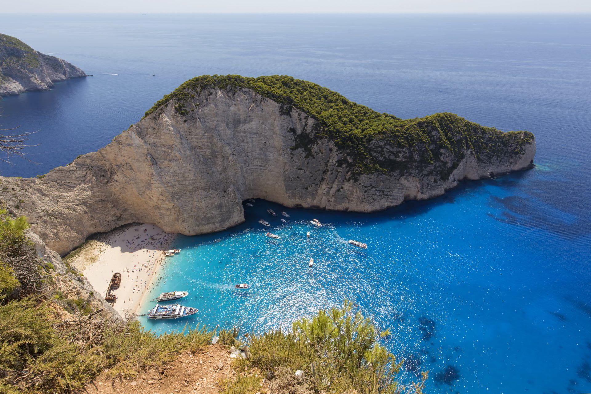 A small island in the middle of the ocean with boats in the water.