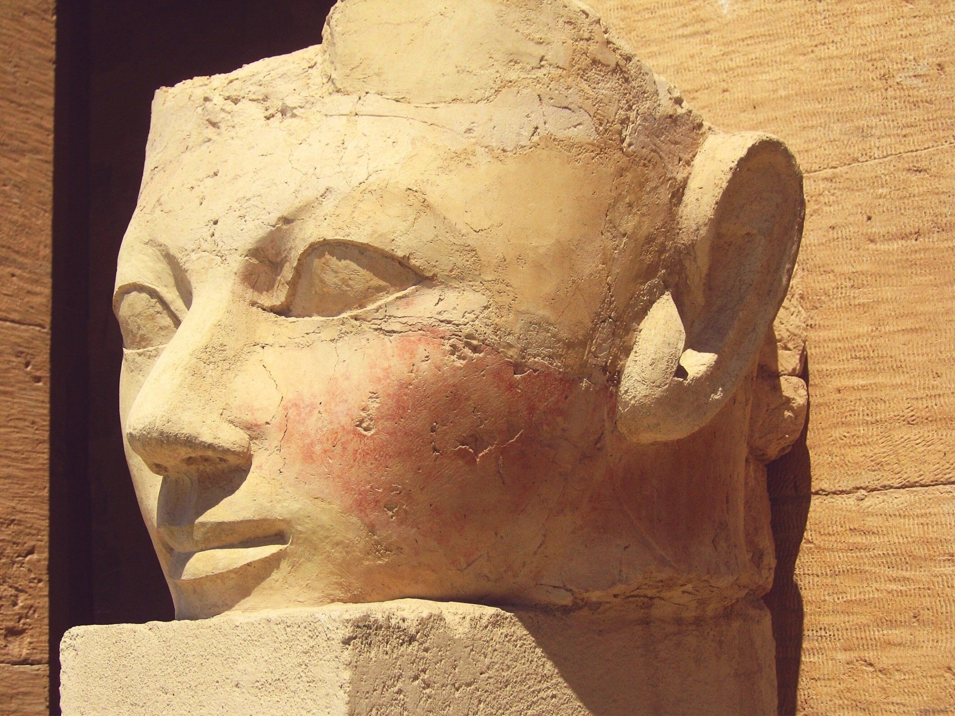 A statue of a man 's head is sitting on a brick wall