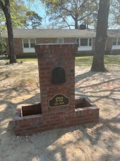 Brick mailbox with address 1732 and a black mailbox, in front of a house.