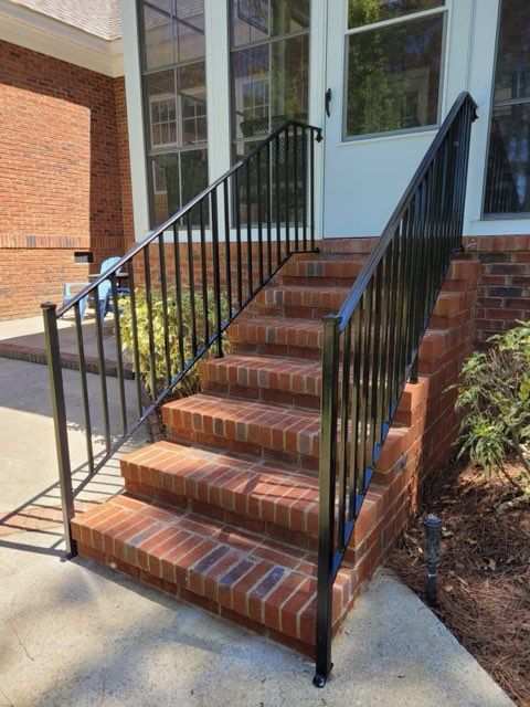 Brick steps leading to a white door, with black metal railings.