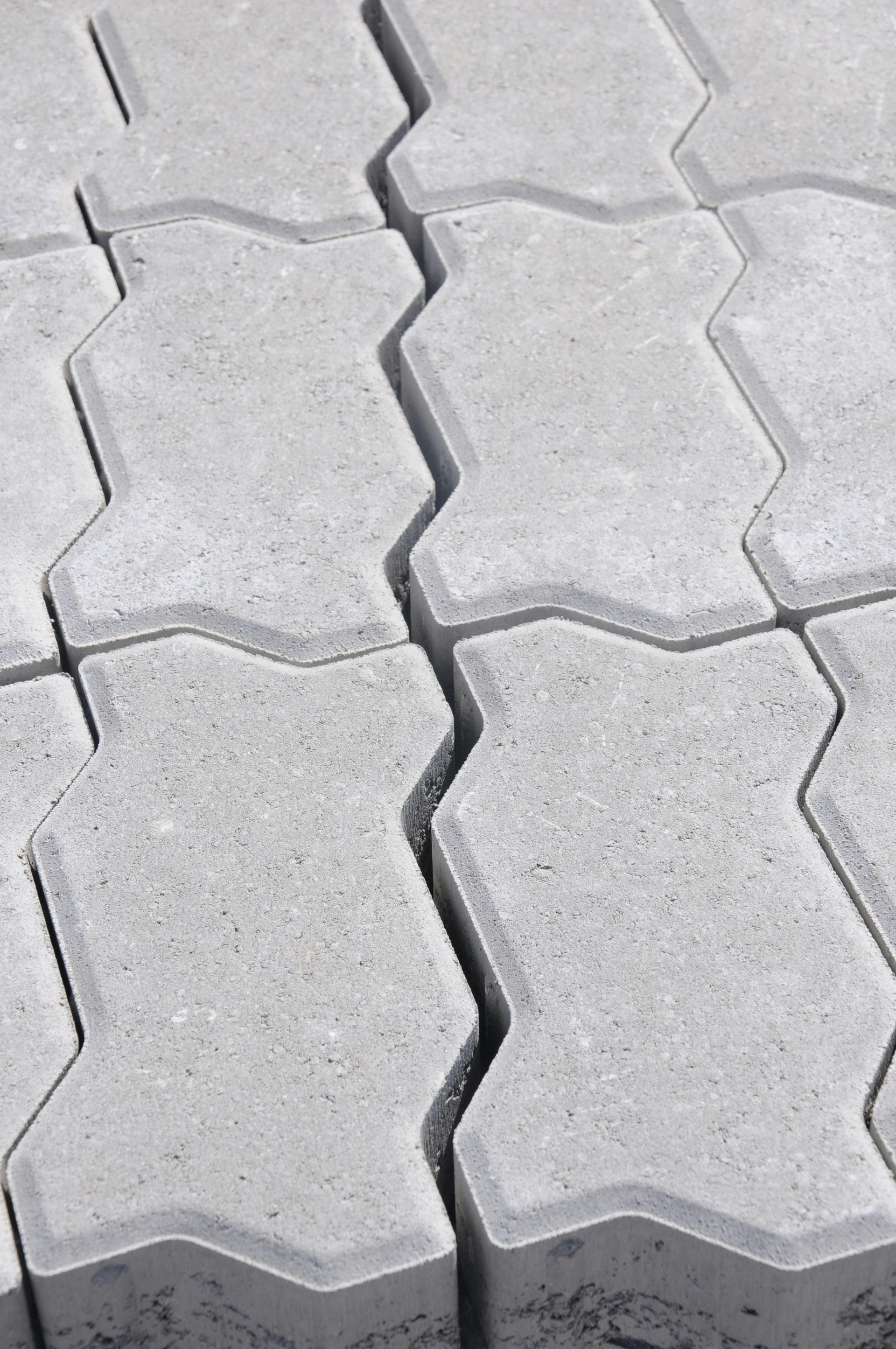 Gray interlocking concrete pavers in a zig-zag pattern, stacked closely together.