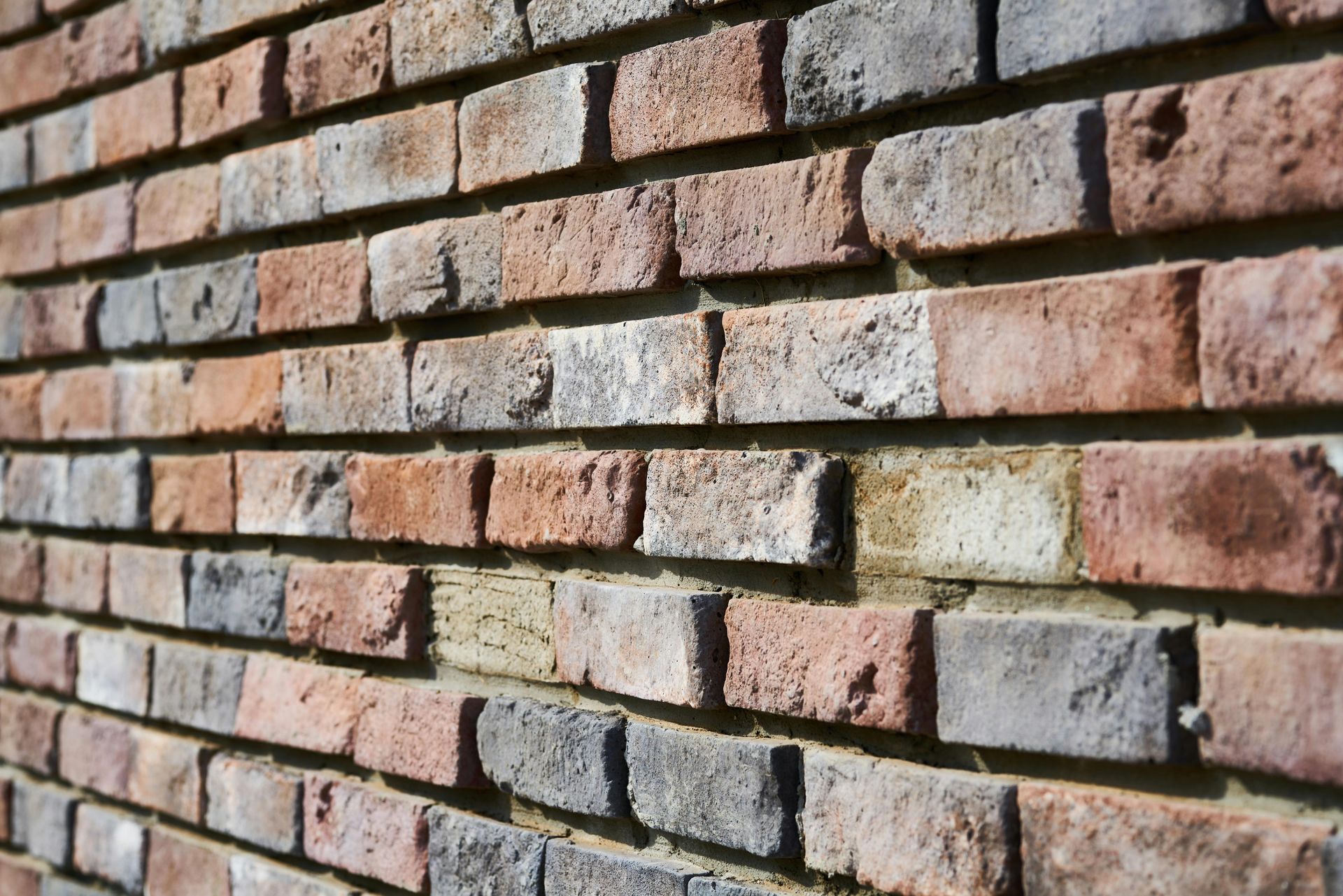 Brick wall, red, brown, and gray bricks arranged in a pattern with visible mortar.