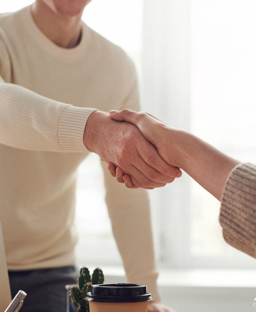 Een man en een vrouw schudden elkaar de hand voor een kopje koffie.
