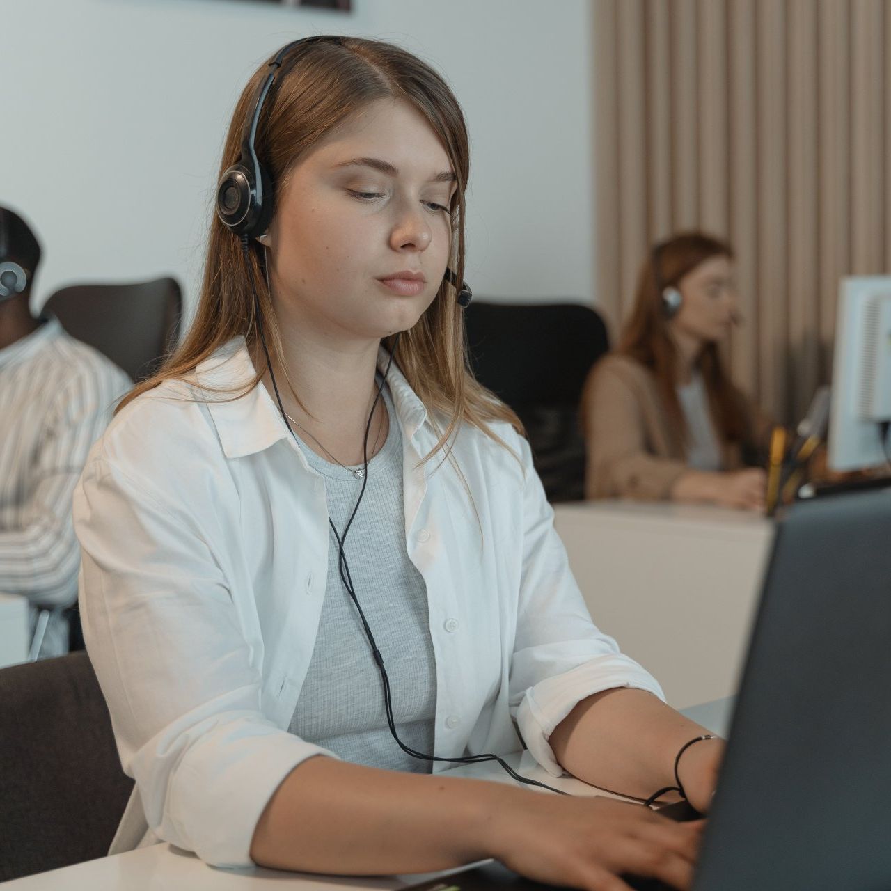 Een vrouw met een koptelefoon gebruikt een laptopcomputer.