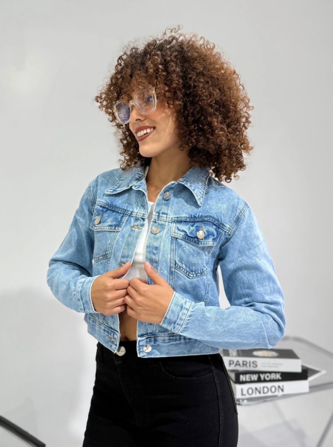 Una persona está abotonando una chaqueta vaquera azul claro con detalles de pedrería.