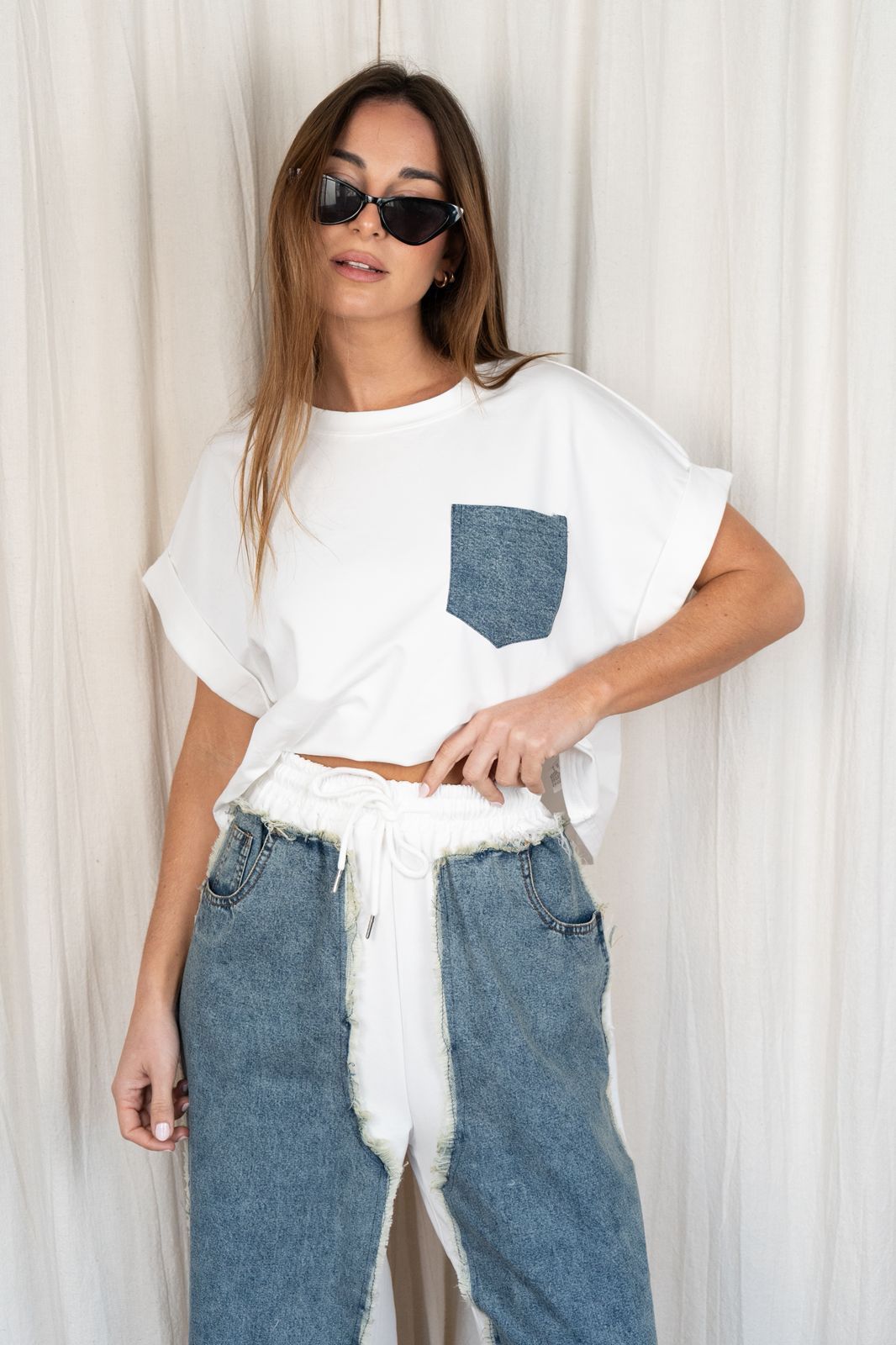 Mujer con gafas de sol, camiseta blanca con bolsillo vaquero y pantalones vaqueros azules,