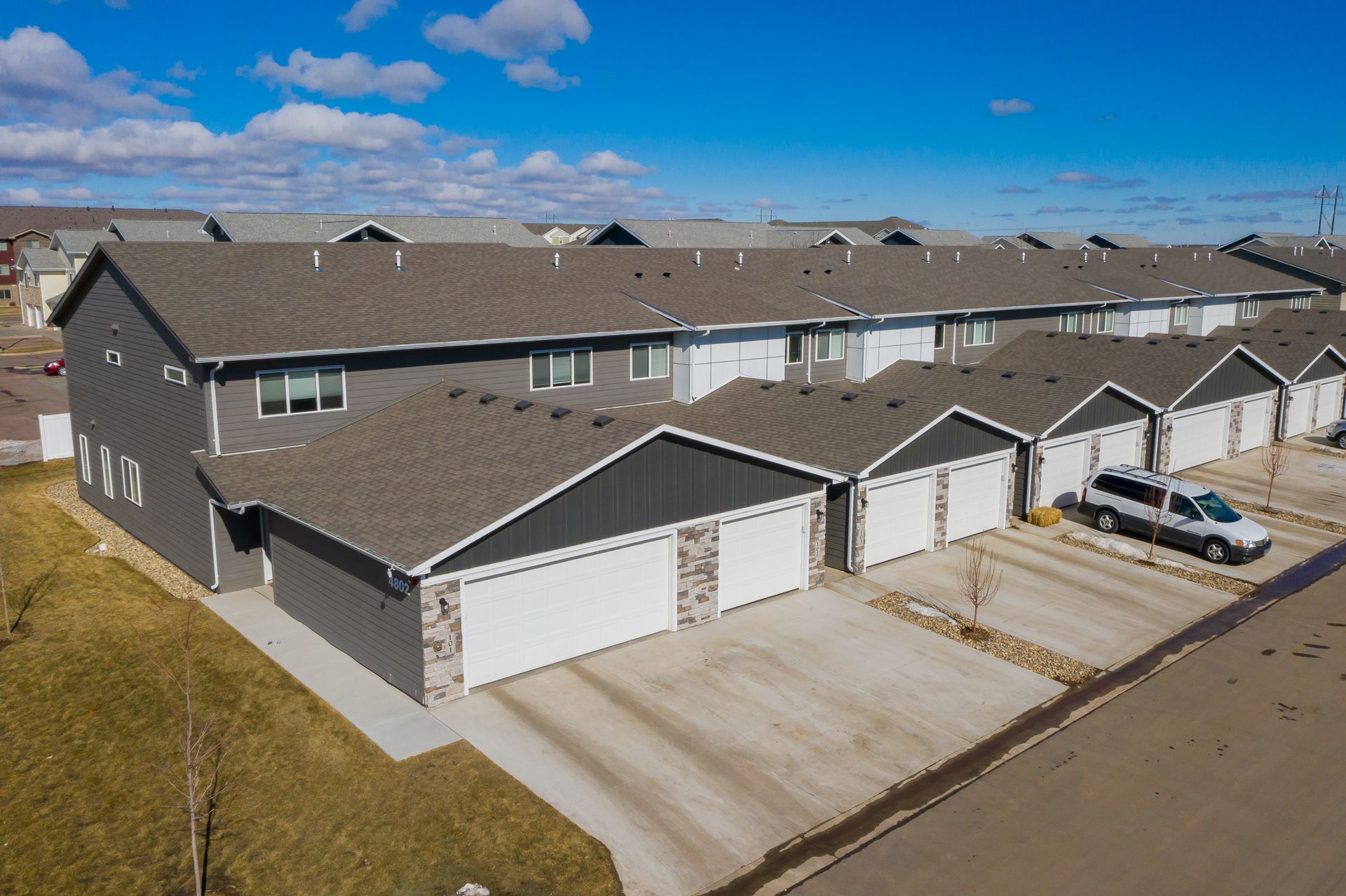 An aerial view of a row of apartment buildings with cars parked in front of them.