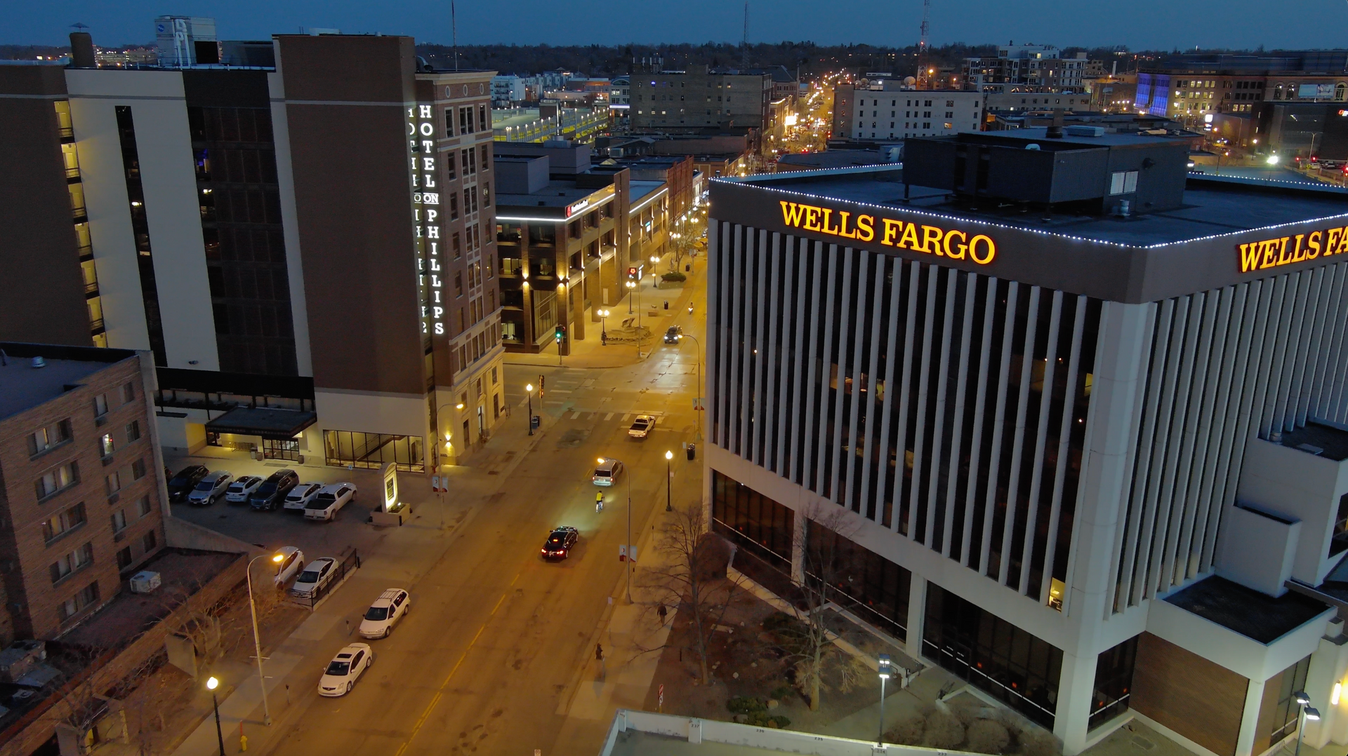 An aerial view of a city at night with a wells fargo building in the foreground