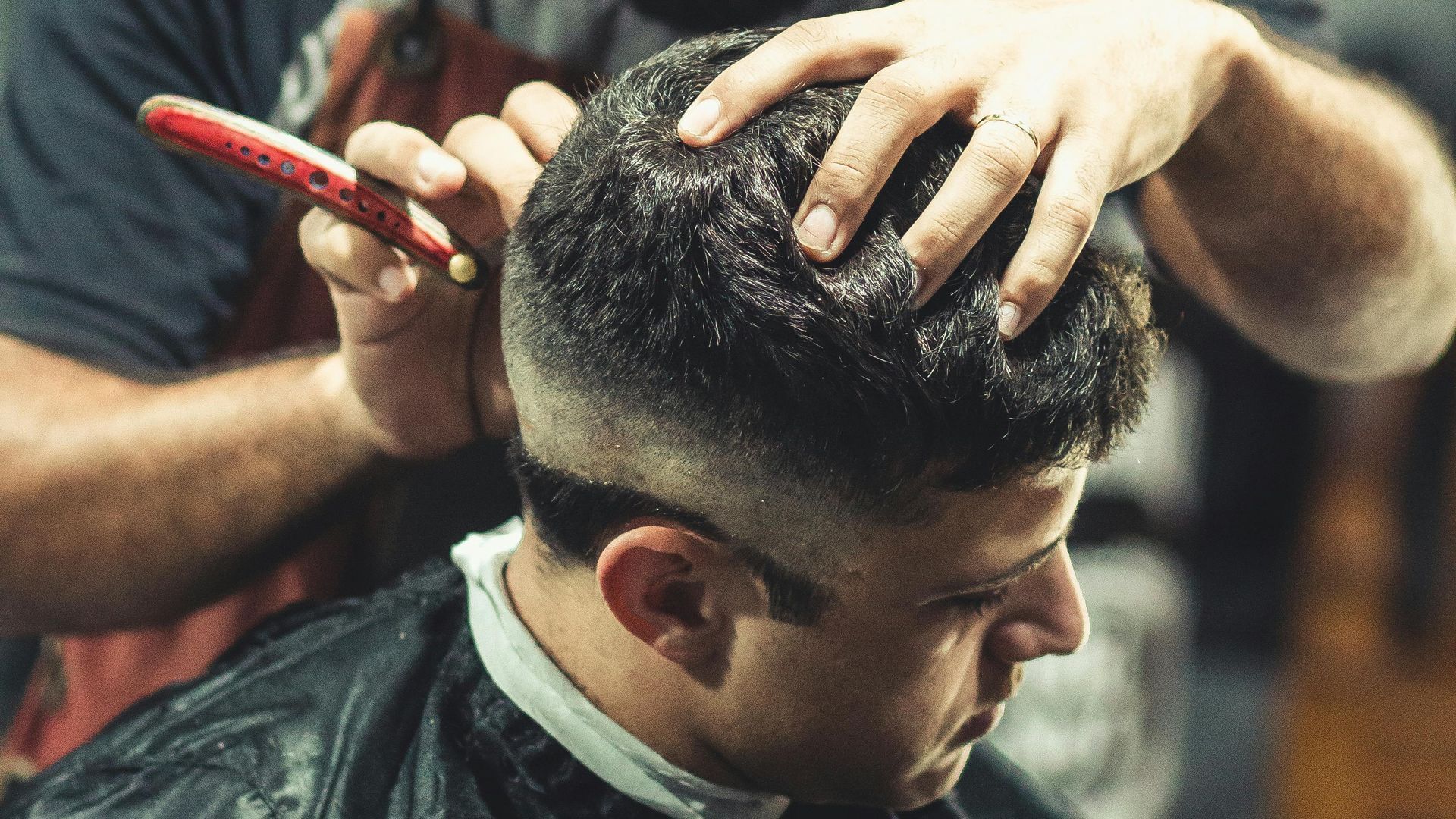 A man is getting his hair cut by a barber in a barber shop.