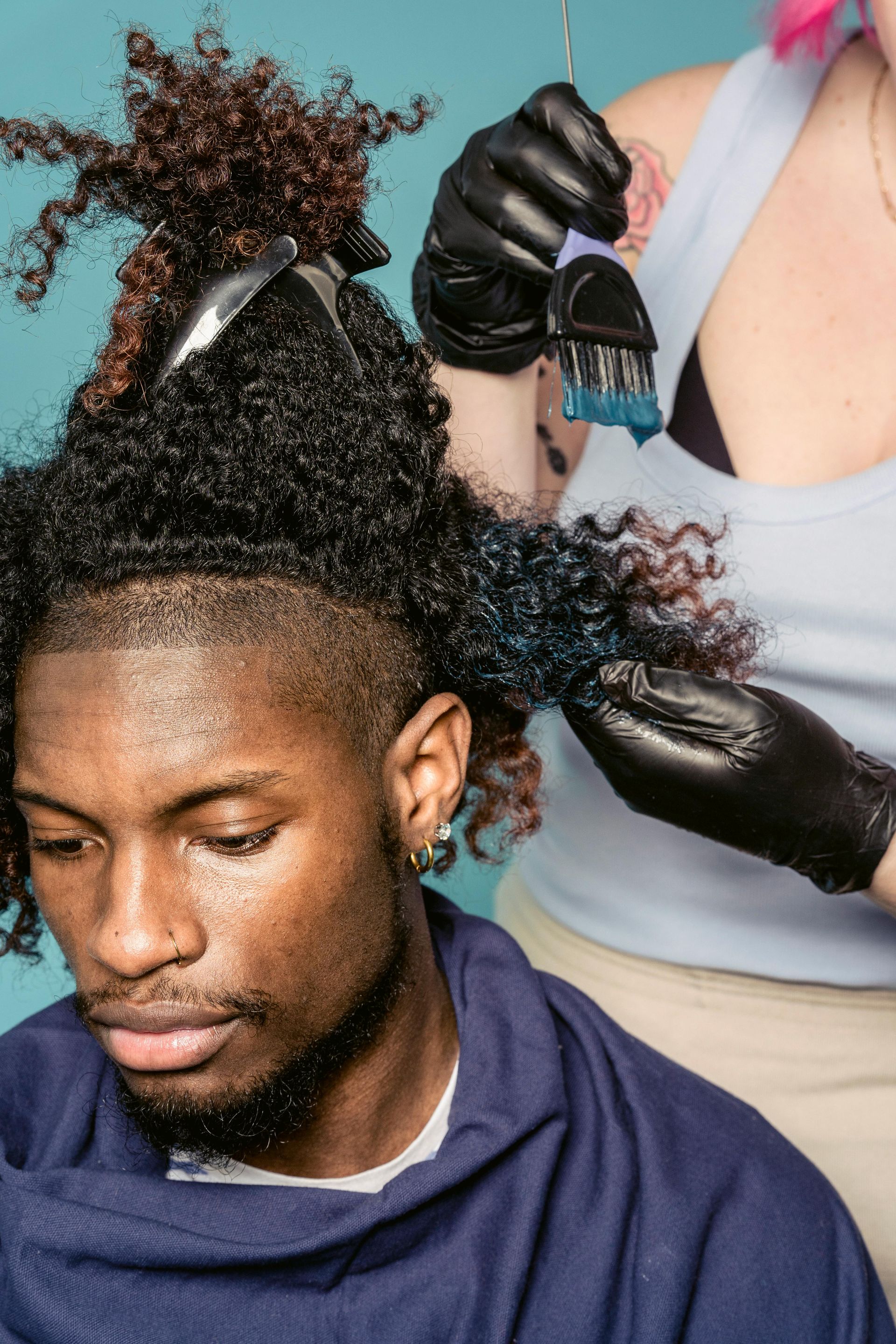 A man is getting his hair dyed by a woman.
