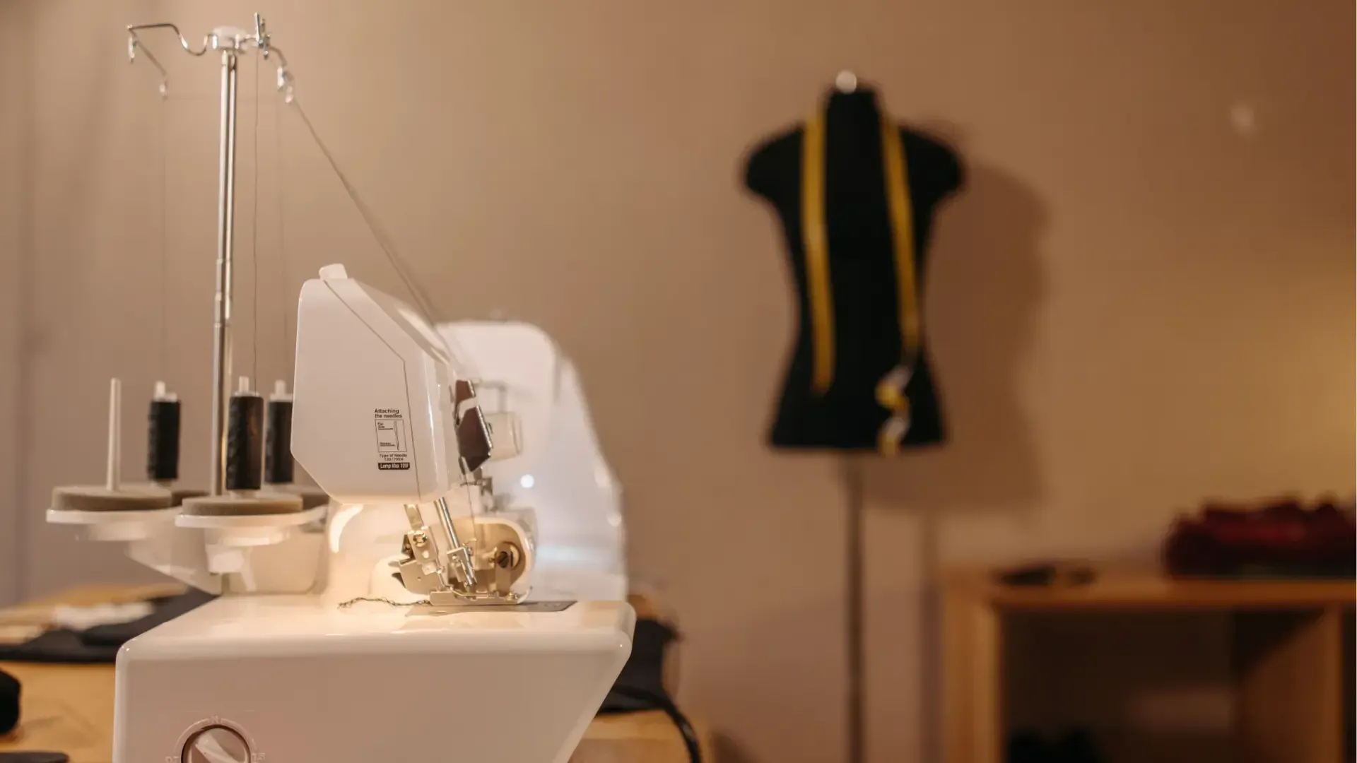 A sewing machine is sitting on a table in a room next to a mannequin.