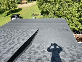 Vue d'un toit recouvert de bardeaux d'asphalte et d'une section plate gris foncé ; l'ombre d'une personne est projetée sur le toit.