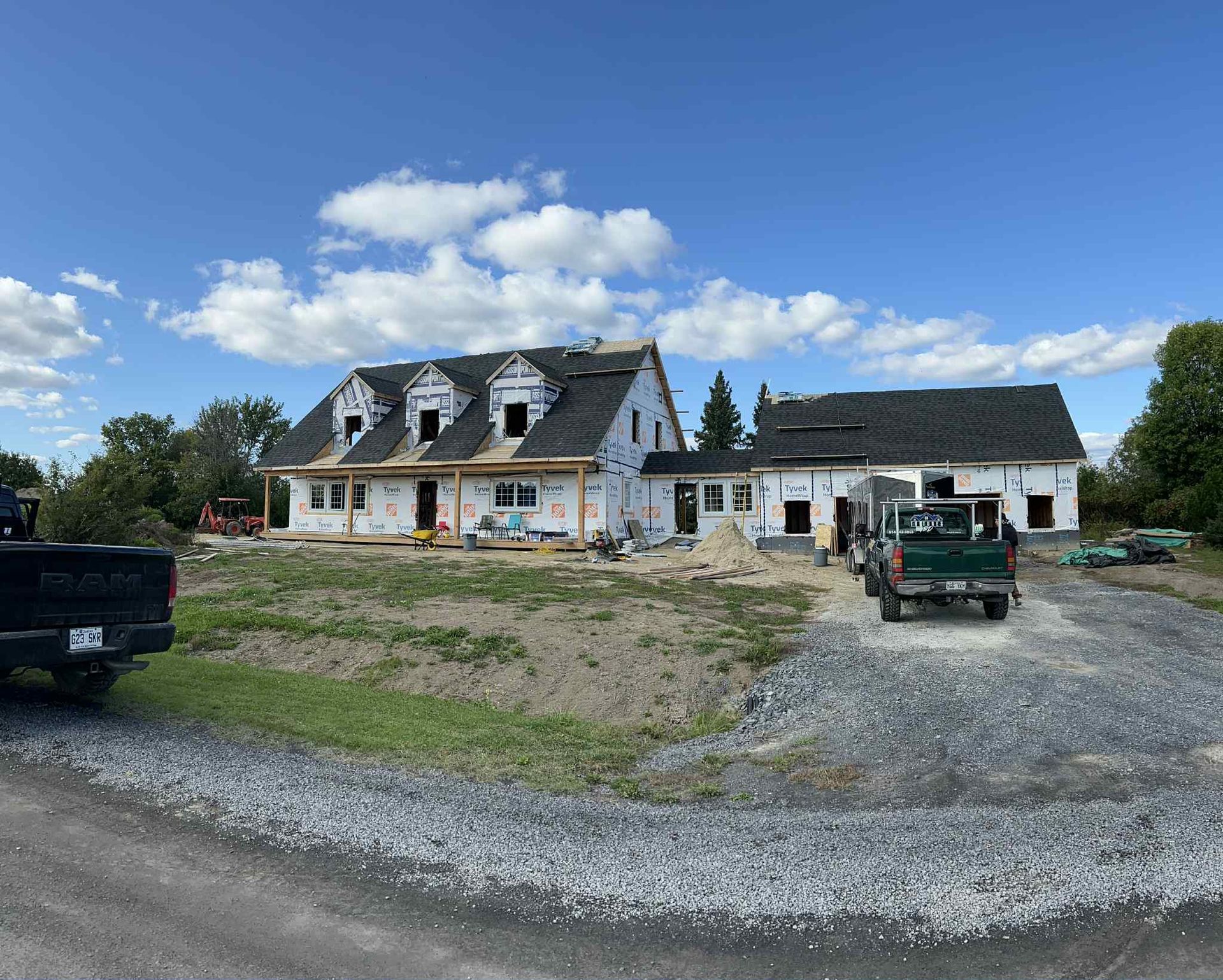Maison en construction avec charpente apparente, toiture sombre et ciel bleu.
