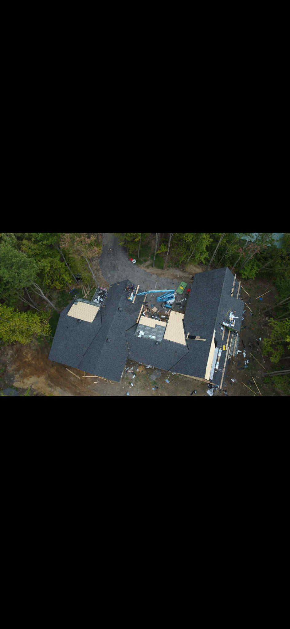 Vue aérienne d'un bâtiment au toit sombre, entouré d'arbres et d'une cour claire.
