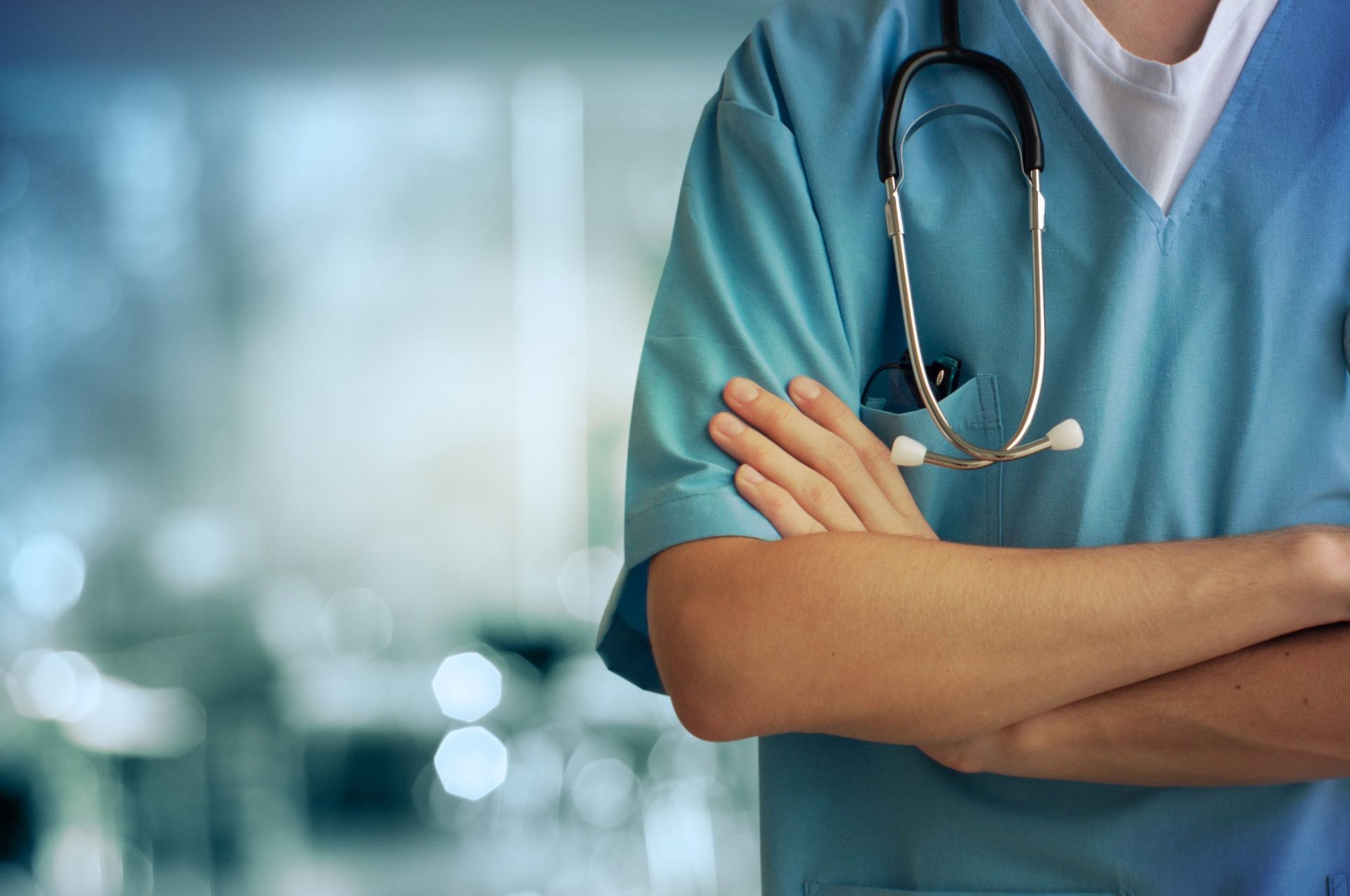 A close up of a doctor with his arms crossed and a stethoscope around his neck.