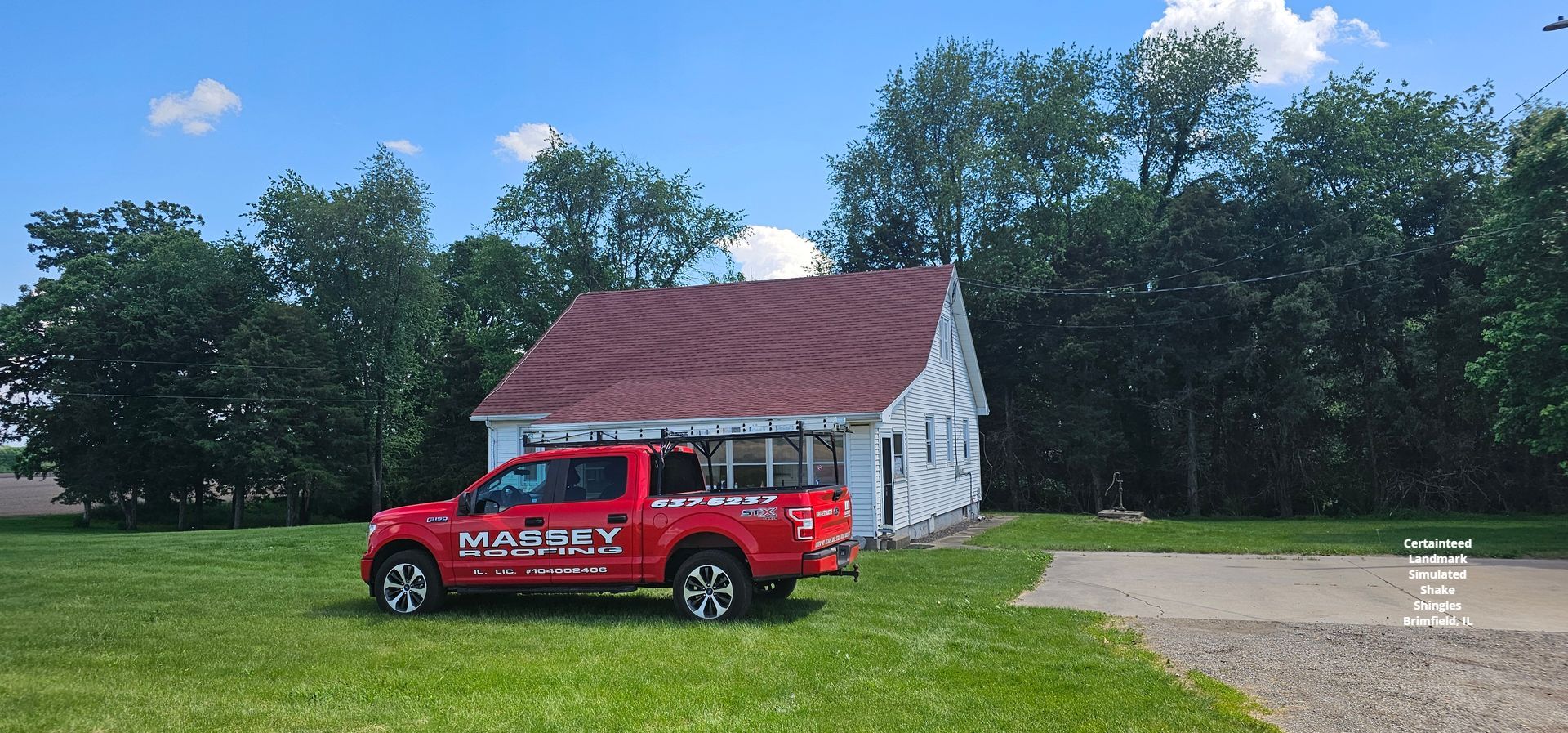 A red truck is parked in front of a small white house.