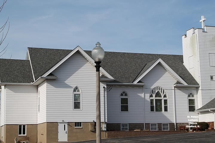 A white building with a gray roof and a street light in front of it