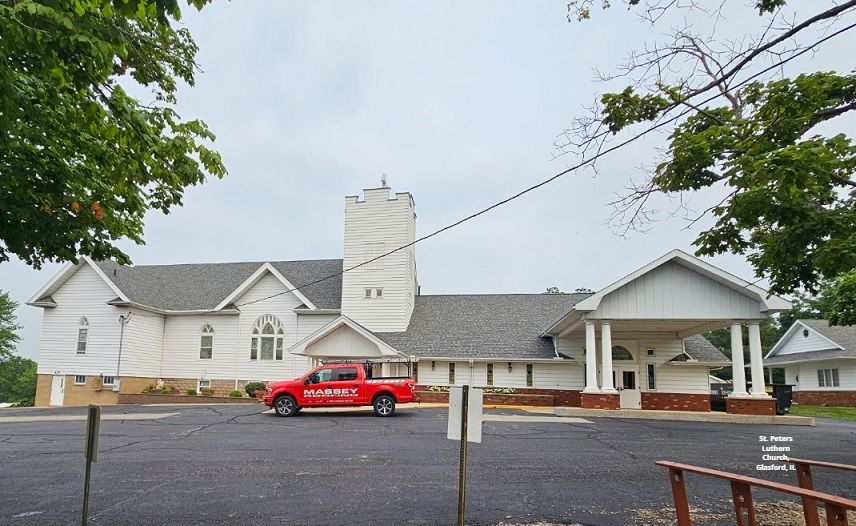 A red truck is parked in front of a large white building
