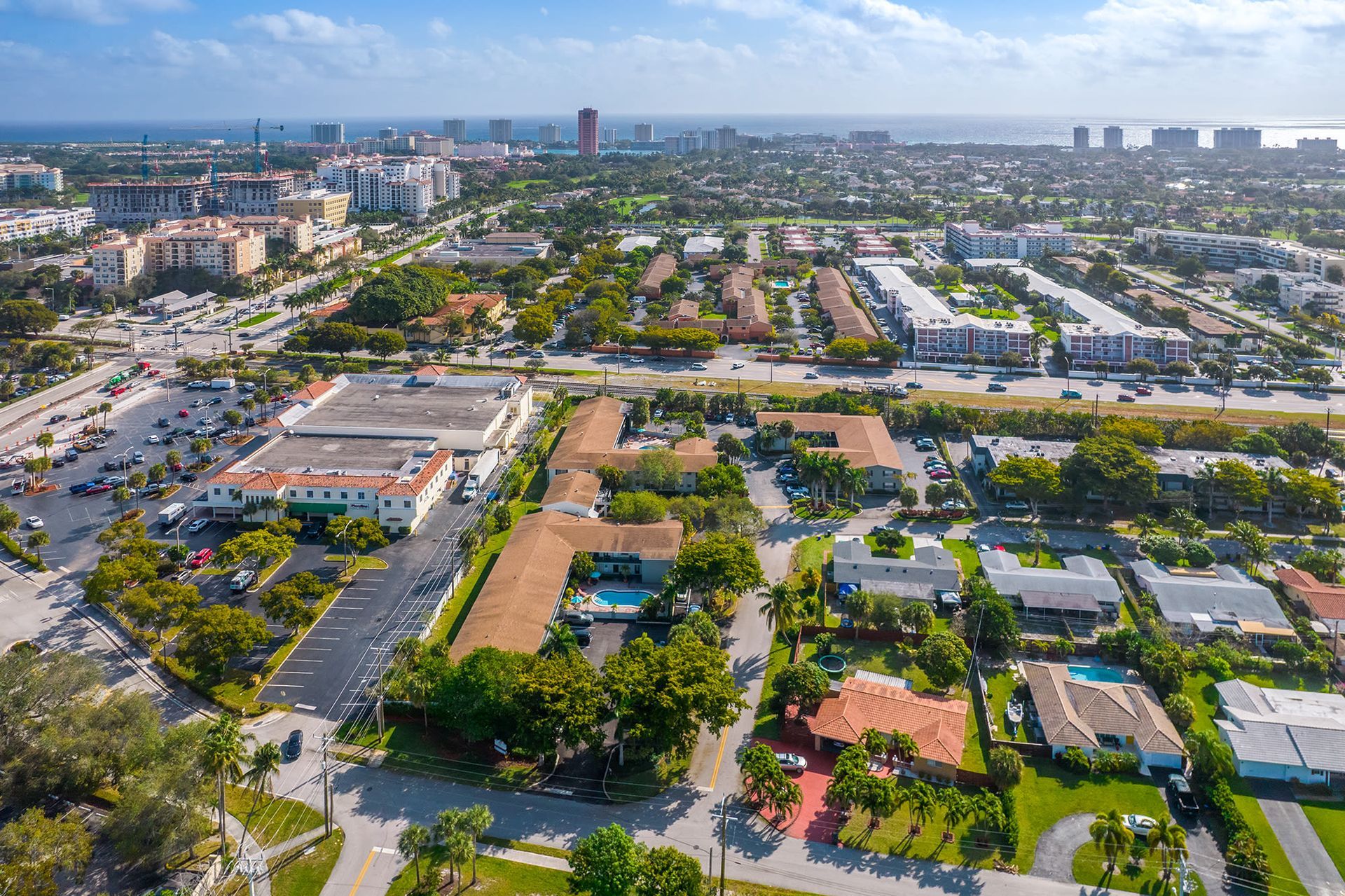 Aerial view of a coastal apartment community with a pool and surrounding buildings.
