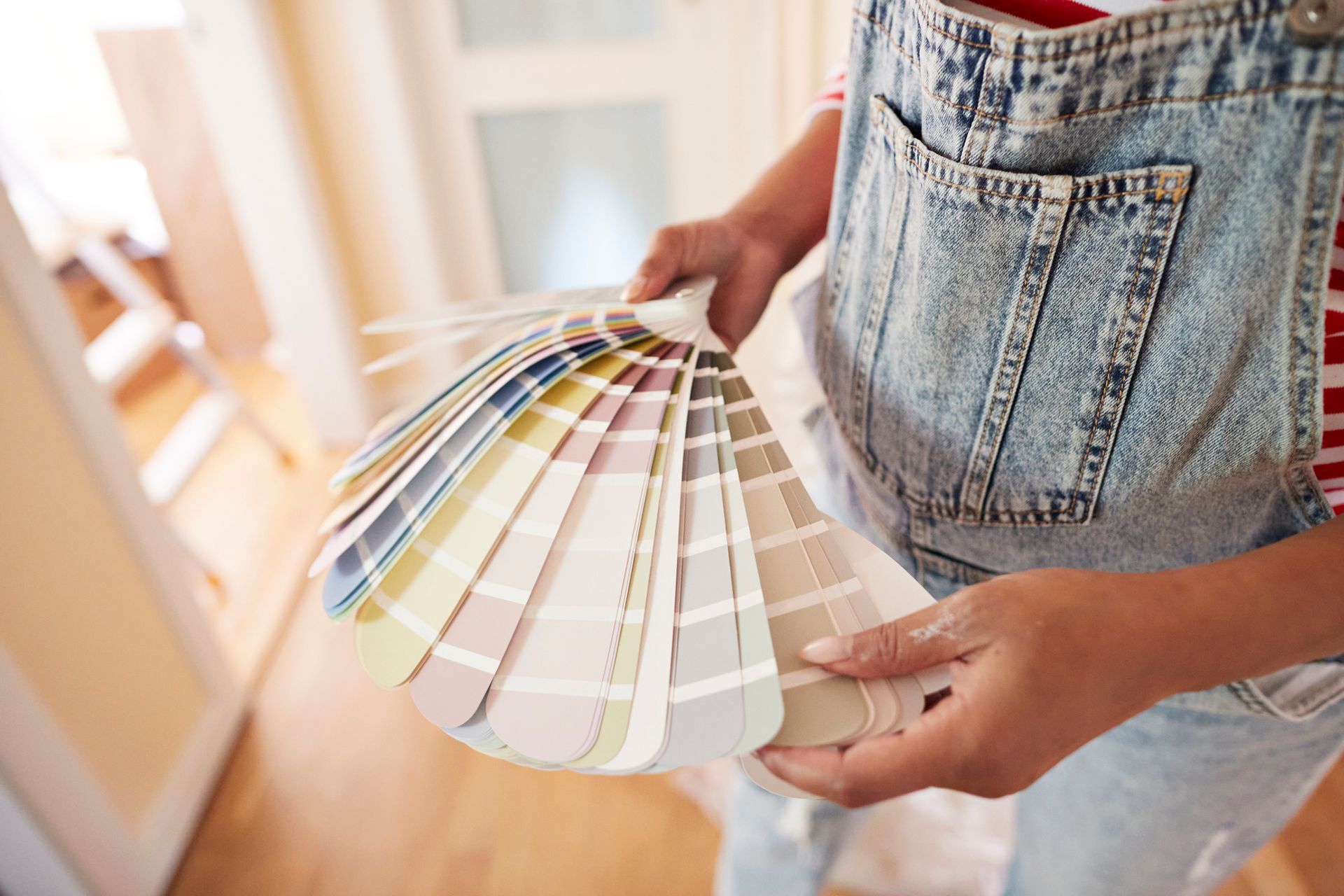 A woman is holding a fan of paint samples in her hands.