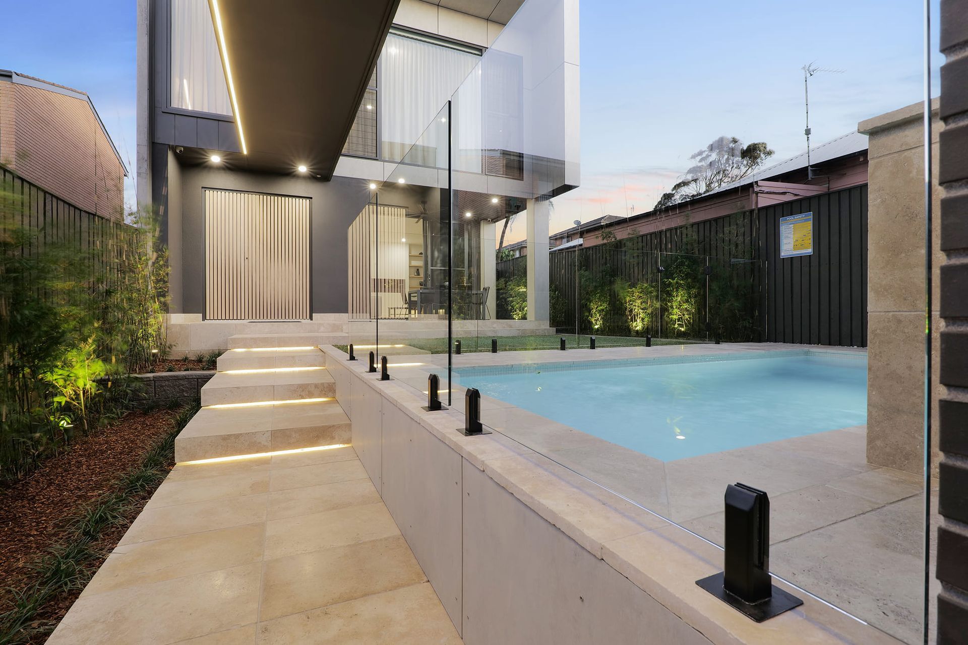 A Swimming Pool With Stairs Leading Up To It At Dusk — Star Glass Design Pty Ltd in Mayfield, NSW