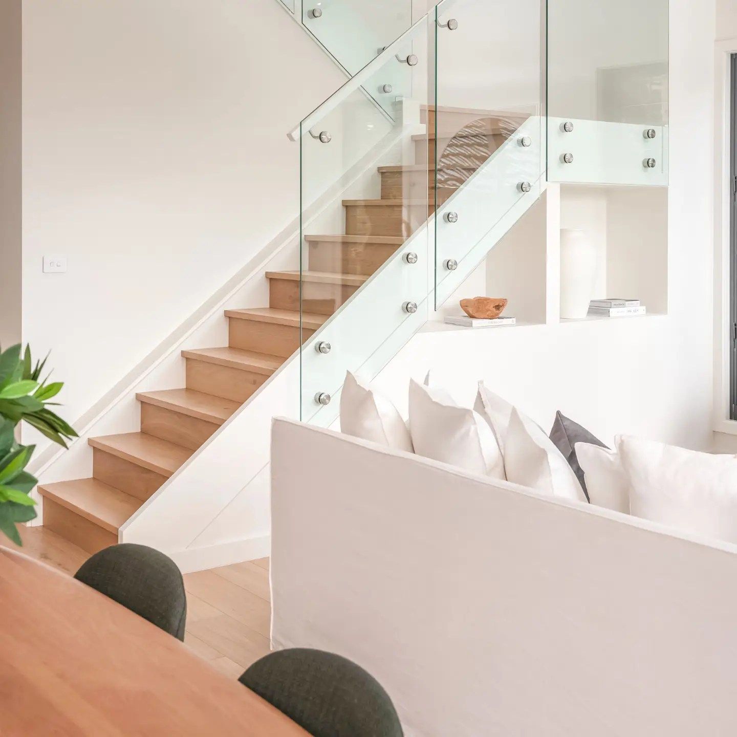 Loungeroom With White Lounge And Timber Staircase With Glass Panels Acting As A Guard Rail — Star Glass Design Pty Ltd in Mayfield, NSW