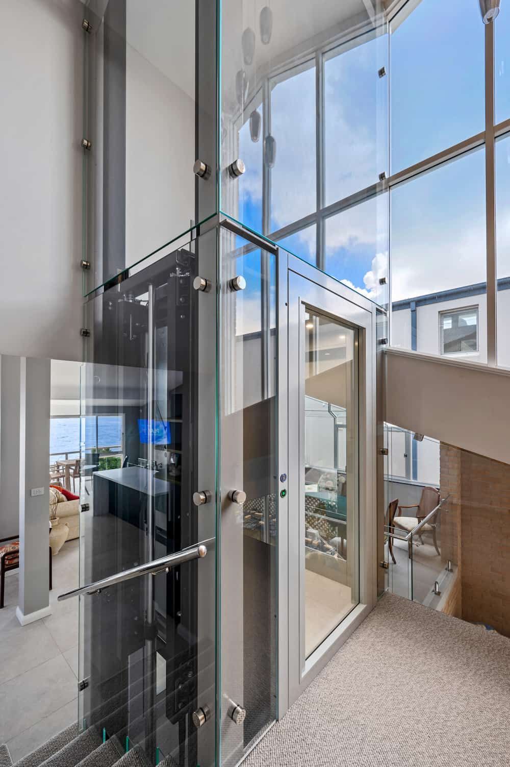 A Glass Lift In A House Next To Stairs — Star Glass Design Pty Ltd in Mayfield, NSW