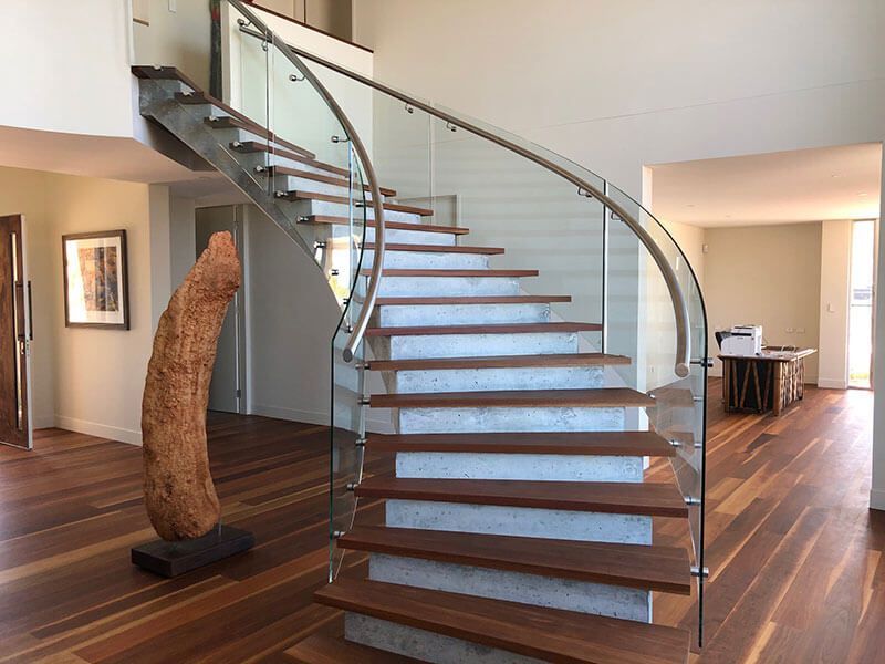 A Curved Staircase With A Glass Railing In A Living Room — Star Glass Design Pty Ltd in Mayfield, NSW