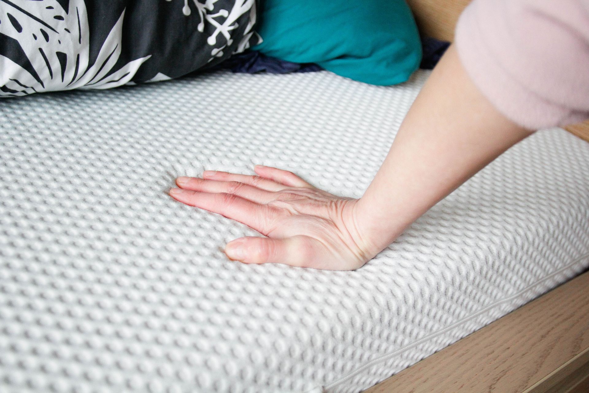 A Person Is Touching a Mattress With Their Hand — Lakeland, FL — Thomason Furniture & Mattress